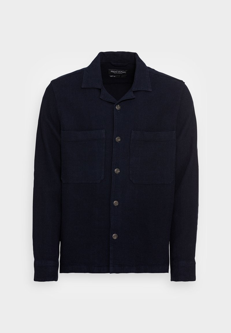 Camicia di lino blu navy con colletto, chiusura a bottoni frontale e due tasche sul petto. Presenta un tessuto testurizzato e maniche lunghe con polsini abbottonati.