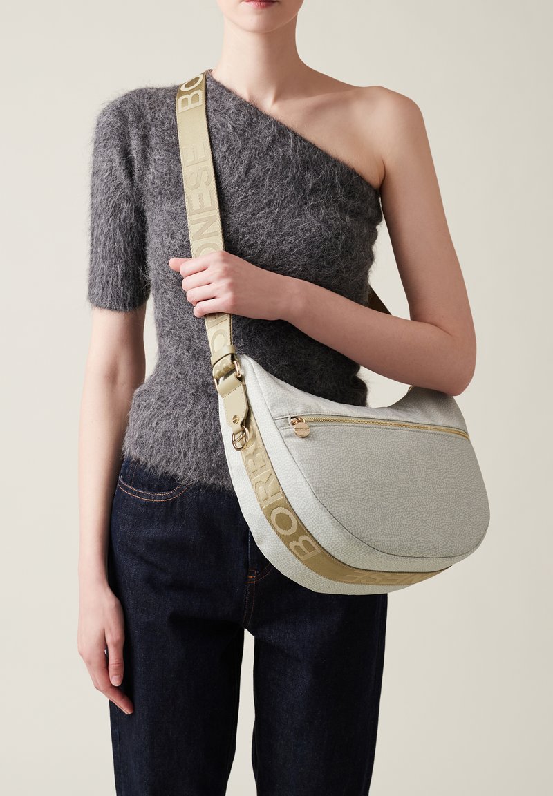 Sac hobo en cuir texturé gris clair, avec une fermeture éclair dorée et une sangle beige ornée du logo "BORB". Forme courbée et douce.