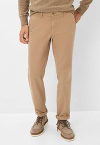 Beige katoenen broek met een slim fit, met een knoopsluiting, opgerolde manchetten en zijzakken, gecombineerd met bruin suède laarzen.