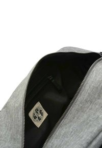 Grau farbener Stoff-Rucksack mit einem Reißverschluss, der ein schwarzes Innenleben und ein Etikett aufweist. Glatte Textur, strukturierte Form und dezentes Design.