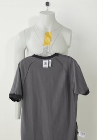 Gray short-sleeve t-shirt with black collar and sleeve accents, made of soft fabric, featuring a tag on the back with logo and care instructions.