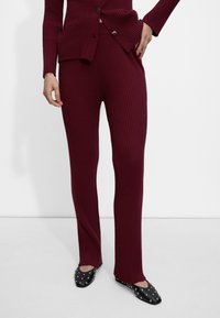 Burgundowa, prążkowana dzianinowa dwuczęściowa komplet składający się z dopasowanych spodni i swetra na guziki, wzbogacony o fakturę materiału, co daje przytulny wygląd.