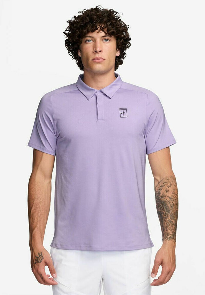 Polo-shirt violet clair avec un col, des manches courtes et un petit logo noir sur la poitrine. Fabriqué en tissu lisse et respirant.