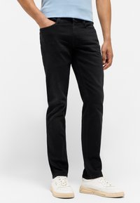 Czarne dżinsy o slim fit, z przednimi kieszeniami i klasycznym paskiem, w połączeniu z białymi tenisówkami.