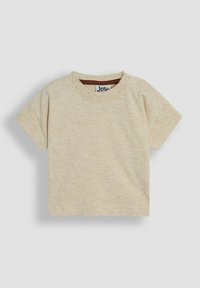 Camiseta de manga corta en suave tejido color beige claro, con un cuello redondo y dos botones a presión en el hombro para facilitar el vestirse.