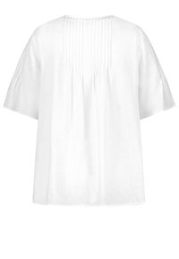 Blouse blanche à manches courtes avec plis nervurés verticaux sur le yoke arrière et les manches, coupe ample, tissu léger.