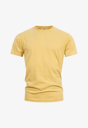 Prosty, jasny żółty bawełniany t-shirt z krótkim rękawem i okrągłym dekoltem, z widoczną metką wewnątrz kołnierzyka, prezentowany na białym tle.