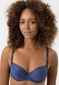 Námorně modrá podprsenka s kosticemi, vyrobená z hladké látky, s květinovými výšivkami na ramínkách v červené a modré barvě. Má kulatý tvar košíčků a nastavitelná ramínka.