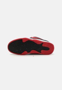Suela de zapato con una base de goma negra texturizada y acentos rojos vibrantes, presentando patrones ondulados para mejorar la tracción y el agarre.