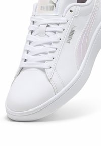 Sneaker bianco in pelle sintetica con dettagli cuciti, lacci piatti e logo riflettente. Punta arrotondata e suola imbottita.