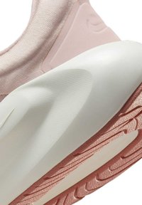 Vaaleanpunaiset lenkkarit, joissa on teksturoidusta kankaasta valmistettu päällinen, kaareva valkoinen välipohja ja vaaleanpunainen kumipohja, jossa on kuvioitu kulutuspinta.