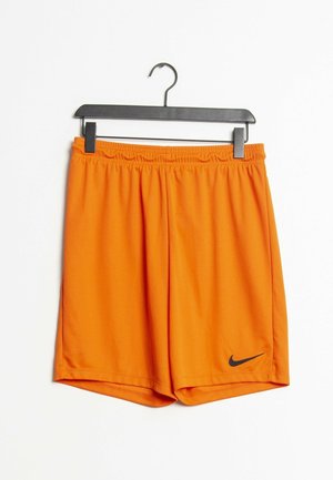 Lyse orange sportsshorts med elastik i taljen og sort Nike swoosh-logo på venstre underben, hængende på en sort bøjle mod en hvid baggrund.