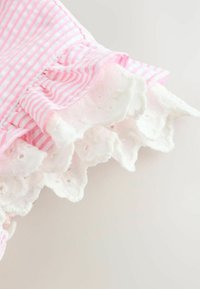 Pink and white striped fabric with gathered ruffles edged by white lace trim featuring small floral embroidery.