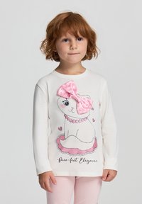 Maglietta a maniche lunghe bianca con una grafica di un gatto che indossa un fiocco a pois rosa e cuoricini, accompagnata dal testo "Purr-fect Elegance."