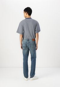 Gestreepte t-shirt met korte mouwen in marineblauw en wit, gecombineerd met rechte blauwe jeans met een bruine leren patch en achterzakken.