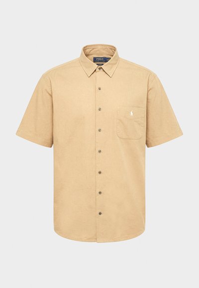 Bėgiškos trumpomis rankovėmis, sagomis užsegama marškinėliai su apykakle, priekyje kišenė su mažu balto siuvinėto logotipo, pateikta ant vientisos spalvos fono.