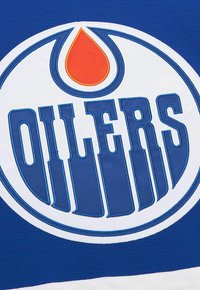 Logo der Edmonton Oilers, das einen blauen und weißen Kreis mit einem roten Öltropfen über dem Wort "OILERS" in blauen Blockbuchstaben auf blauer Fläche zeigt.