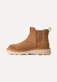 Stivaletti in suede marrone con pannelli laterali elastici, punta tonda e suola in gomma beige. Presentano una linguetta sul retro per una facile calzata.