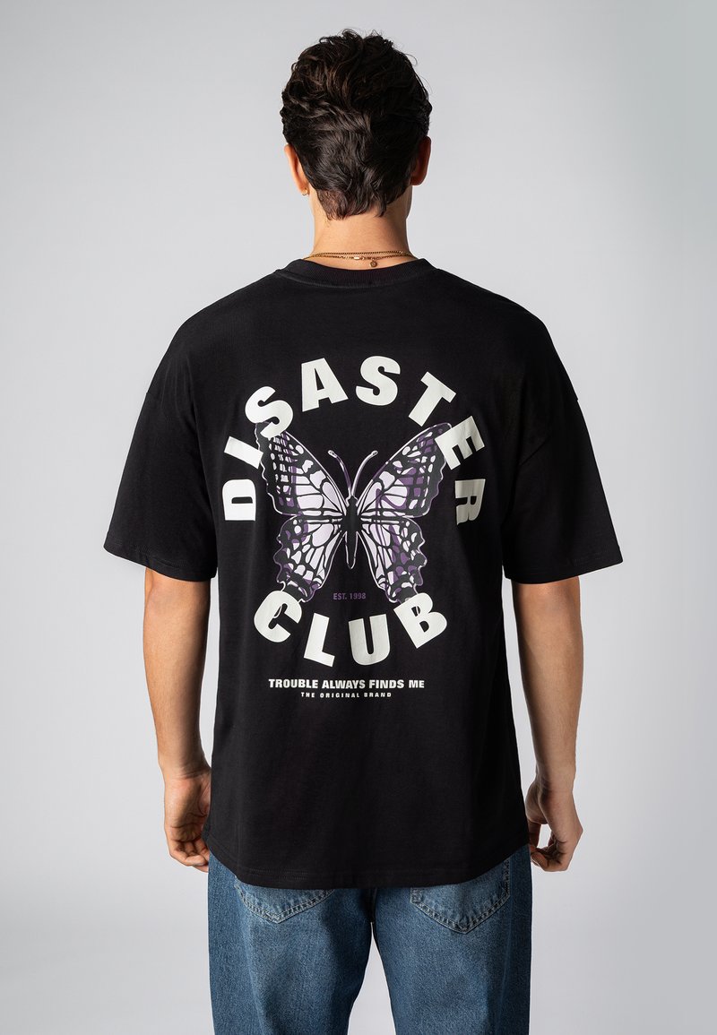 Schwarzes Baumwoll-T-Shirt mit einem großen lila-weißen Schmetterlingsmotiv auf der Rückseite, darunter der Schriftzug "DISASTER CLUB" und ein Slogan.