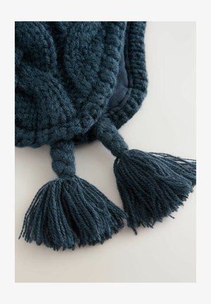 Tissu en tricot teal foncé avec une finition tressée, présentant deux grands pompons aux extrémités, mettant en valeur la texture et la riche couleur.