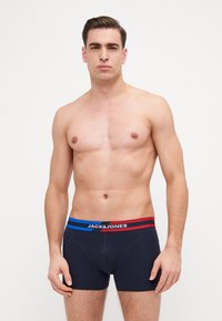Boxers de couleur bleu marine avec un design ajusté. La taille élastique présente des rayures rouges et bleues avec le logo "JACK & JONES". Texture en coton lisse.