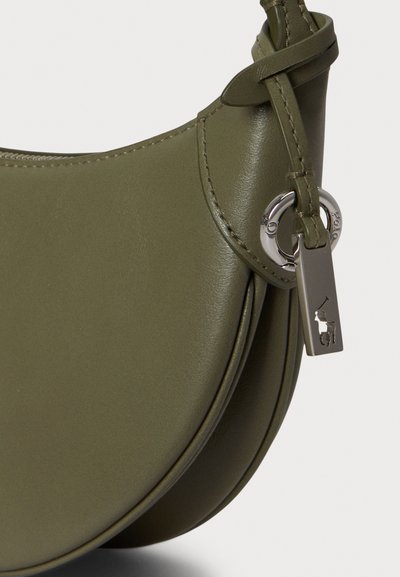 Borsa a tracolla in pelle verde oliva con forma arrotondata, cuciture visibili e un accessorio portachiavi in metallo con logo. Texture liscia.