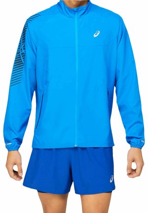 Blaue sportliche Zip-Jacke mit schwarzen Ärmelstreifen und passenden blauen Shorts mit weißem Logo am linken Bein.