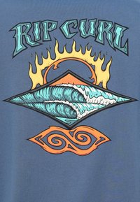 Μπλε μπλουζάκι με ζωηρή γραφική απεικόνιση κυμάτων μέσα σε διαμάντι, διακοσμημένο με μοτίβο ήλιου και φλόγας, καθώς και στροβιλιζόμενα πορτοκαλί σχέδια.