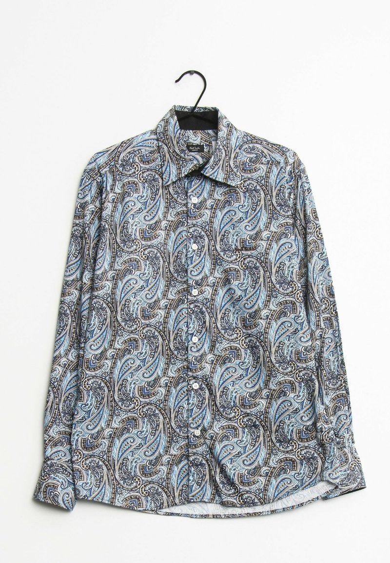 Långärmad skjorta med knappar i blå, svart och vit paisleymönster som hänger på en svart galge mot vit bakgrund.