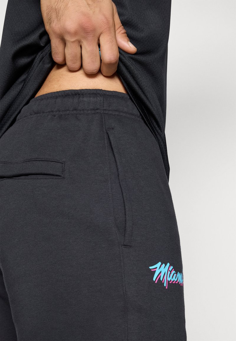 Graue Sweatpants aus weichem Stoff mit einem gestickten "Miami"-Logo in Türkis und Pink. Besitzt eine Seitentasche und einen elastischen Bund.
