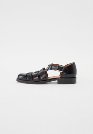 Schwarze Leder-Sandale mit geschlossenem Zehenbereich, mehreren Riemen, Schnallenverschluss, niedrigem Absatz und offenen Seiten, von der Außenseite gezeigt.