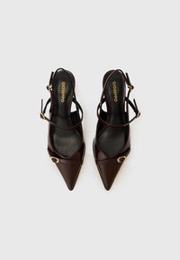Brown patent leather slingback heels with pointed toes, strap detailing, and gold hardware accents. Smooth texture and sleek design.