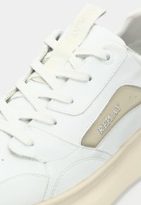 Weißer Sneaker mit einem Obermaterial aus glattem Leder, beigen Akzenten und einer verstärkten Zehenpartie. Verfügt über flache Schnürsenkel und ein Logotag auf der Zunge.
