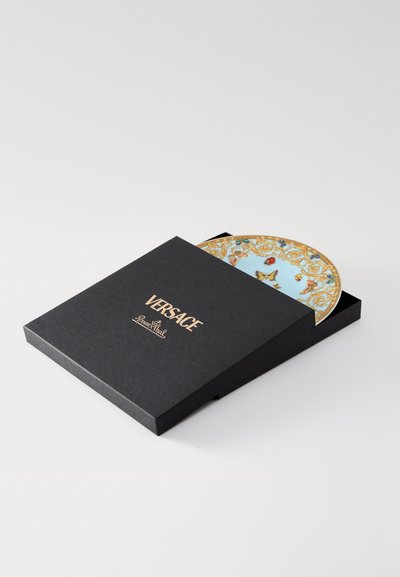 Διακοσμητικό πιάτο Versace σε μαύρο κουτί με χρυσά γράμματα. Το πιάτο έχει ανοιχτό μπλε φόντο με περίτεχνα χρυσά και π�ολύχρωμα σχέδια.