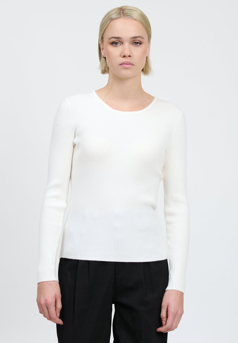 Top lungo a maniche lunghe bianco a costine realizzato in un tessuto elasticizzato con scollatura rotonda. La vestibilità è aderente al corpo e la texture è liscia.