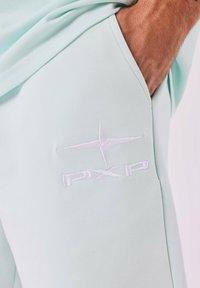 Jogging en vert menthe clair en tissu doux avec un logo "PXP" brodé en blanc et un accent étoile sur la poche de la cuisse gauche.