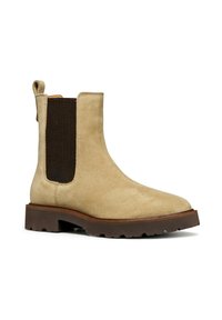 Botas de ante beige hasta el tobillo con paneles elásticos en los laterales, suela de goma marrón, puntera redonda y una lengüeta en la parte posterior para facilitar su colocación.