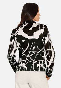 Zwart-wit abstract patroonjasje van stof, met lange mouwen, een kraag en een getailleerde pasvorm. Achteraanzicht afgebeeld.