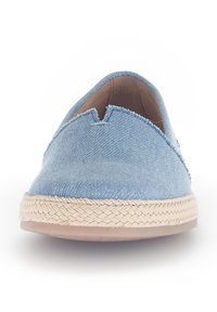 Zapatos slip-on de lona azul claro cuentan con una suela de yute trenzado y un corte bajo. La parte superior tiene un acabado texturizado con un corte en forma de V en la parte delantera.