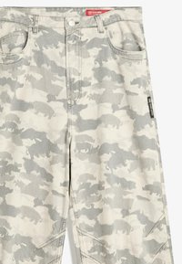 Sive i bijele kamuflažne hlače s siluetama medvjeda, prednji džepovi, petlje za remen i crvena oznaka brenda na struku i sa strane.