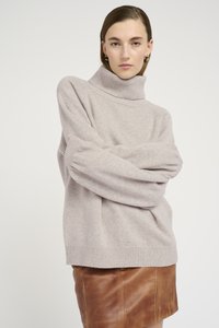 Maglione a collo alto grigio chiaro con vestibilità rilassata, con polsini e orlo a costine. Abbinato a una gonna in pelle marrone, che mette in mostra morbide texture e forme.