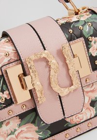 Blommönstrad faux leather-väska med en rosa texturerad klaff, detaljer i guld och nitar. Utrustad med en dekorativ metallspänne.