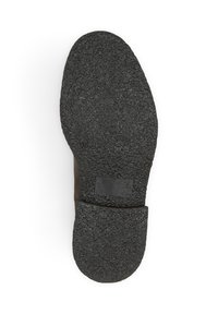 Semelle de chaussure en caoutchouc noir avec une surface texturée, présentant une pointe arrondie et un design plat. Inclut une zone rectangulaire lisse près du talon.