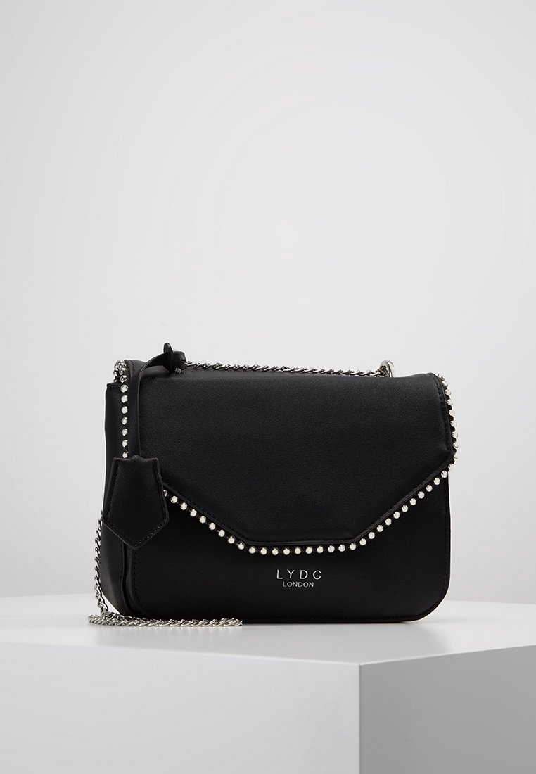 Borsa a tracolla nera in pelle sintetica con tracolla a catena, caratterizzata da un pattina a busta, dettagli a perle lungo i bordi e logo decorativo.