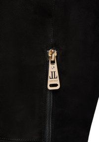 Tirante dorato con incisione "JL LORIBLU" su tessuto in suede nero, con un piccolo strass trasparente incastonato sopra le lettere.