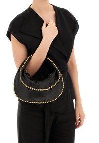 Borsa in pelle nera a forma di mezzaluna con dettagli in borchie dorate lungo i bordi. La borsa ha una consistenza morbida ed è dotata di chiusura con zip.