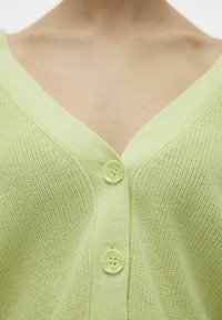 Cárdigan verde claro con diseño de cuello en V, tejido de punto texturizado y dos botones frontales con un suave brillo.