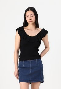 Svart ribbet tanktop med volangkant, paret med et miniskjørt i blå denim, som viser en tettsittende design og glatt tekstur.