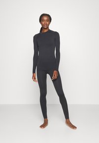 Μαύρη μπλούζα με μακριά μανίκια και αντίστοιχες κολάν φτιαγμένα από εφαρμοστό, ελαστικό υλικό, με λεπτομέρειες ραφής και στρογγυλή λαιμόκοψη.