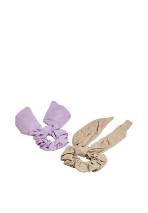 Dva textilné scrunchie s pripnutými mašličkovými viazačkami, jeden svetlofialový a druhý béžový, zobrazené na bielom pozadí.